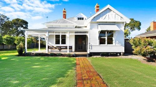 a white house with a porch and a lawn at Charming Heritage Retreat in Sale
