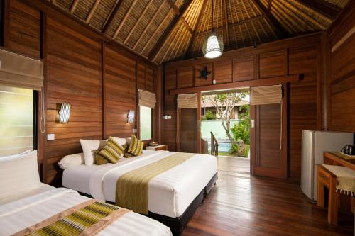 two beds in a room with wooden walls at Gecko Villa & Bungalows in Nusa Lembongan