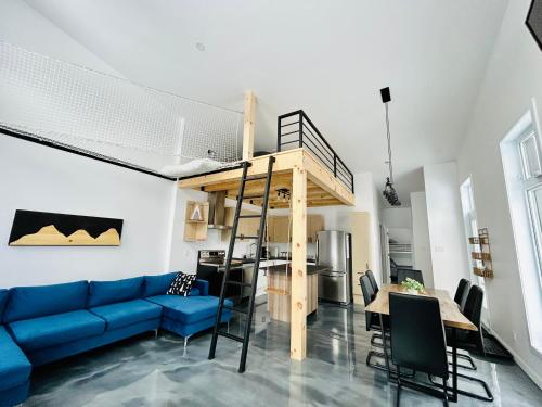 a living room with a blue couch and a loft bed at La remontee in LʼAnse-Saint-Jean