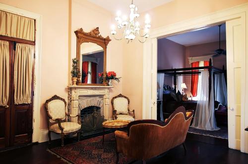 a living room with a fireplace and two chairs and a mirror at The Olivier House Hotel in New Orleans