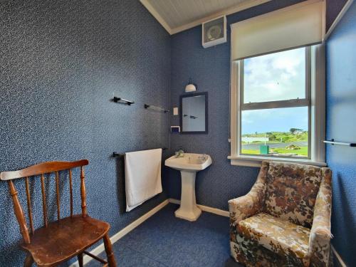 a bathroom with a sink and a chair and a window at Justavacation Beachfront Bach in Riverton