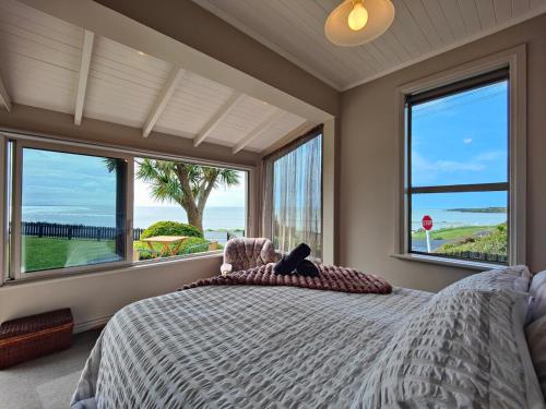 a bedroom with a large bed with a view of the ocean at Justavacation Beachfront Bach in Riverton