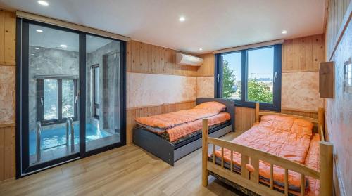 two beds in a room with windows at Diorem Pension in Jeju