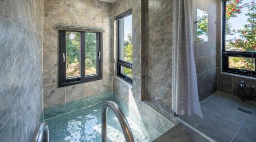 a bathroom with a tub and a shower with windows at Diorem Pension in Jeju