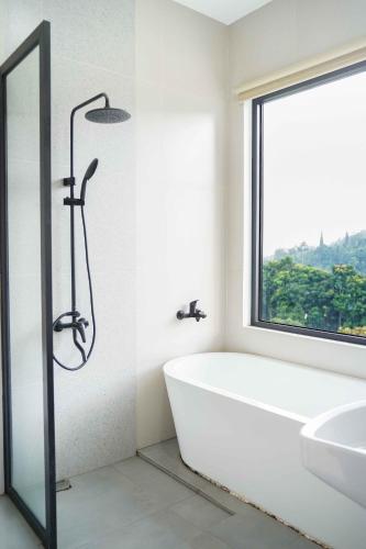 a bathroom with a tub and a sink and a window at Moment Villa in Lembang