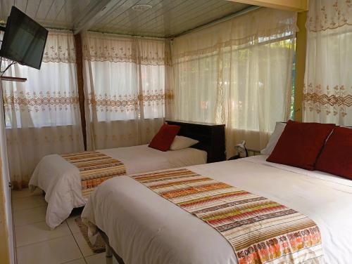 a bedroom with two beds and a tv in it at Hostería Real Parque Tababela in Tababela