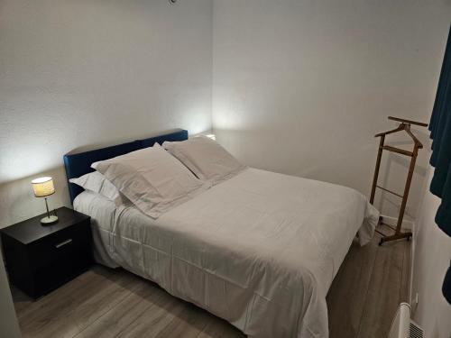 a bed with white sheets and pillows in a bedroom at Appartement paisible in Quévert
