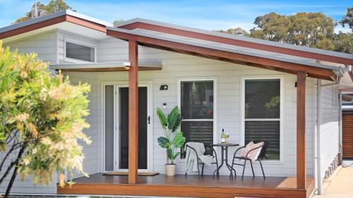 a house with a deck with a table and chairs at Coastal Bungalow in Callala Bay