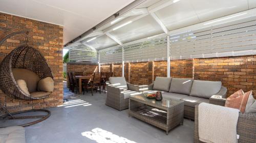 a living room with a couch and a brick wall at Coastal Crush in Callala Beach