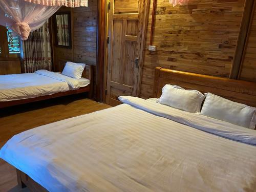 a bedroom with two beds in a wooden cabin at My's Hmong House in Tả Van