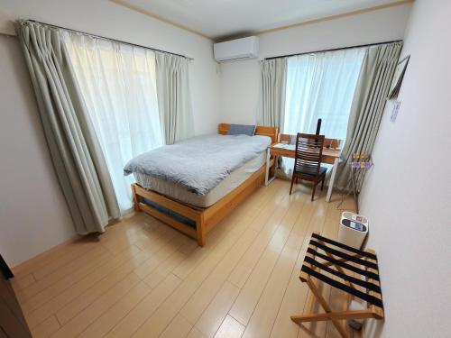 a bedroom with a bed and a desk and windows at Hao Bros. Home in Tokyo