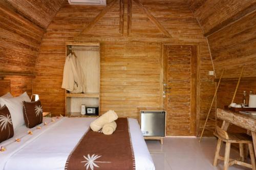 a bedroom with a bed and a wooden wall at Penida Green Palm Cottage in Nusa Penida
