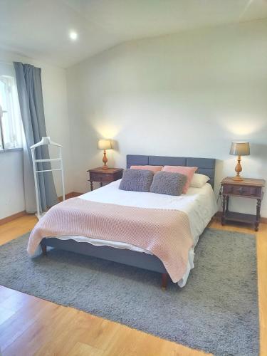 a bedroom with a large bed with two tables and two lamps at Casa da Lameira in Vilar do Ruivo