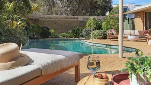 a swimming pool with a hat and a glass of wine at Coolburra in Culburra Beach