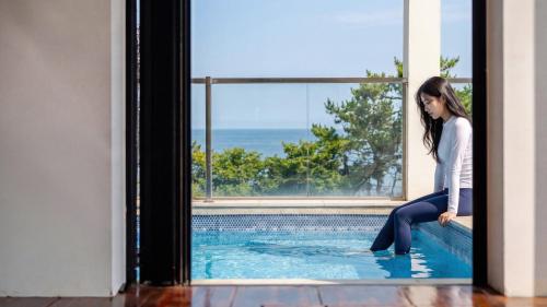 a woman sitting on the edge of a swimming pool at Pohang Sausalito by B-Class Pool Villa in Pohang