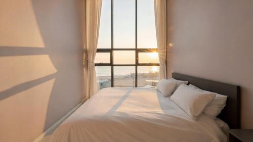 a bed in a room with a large window at Pohang Sausalito by B-Class Pool Villa in Pohang