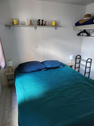 a bed in a room with a blue blanket at FMLODGE mobil home le petit cocon in Valras-Plage