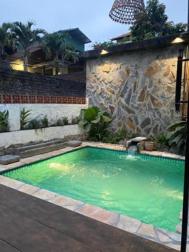 a swimming pool in a yard with a stone wall at Tam Coc Sweet Home in Ninh Binh