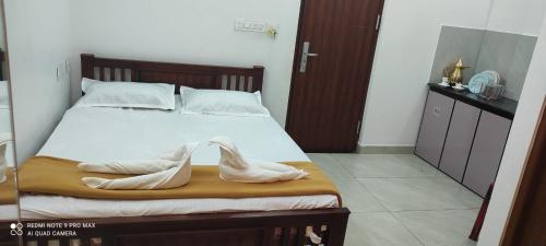 a bedroom with a bed with white sheets and shoes on it at Marari A R Residency in Mararikulam