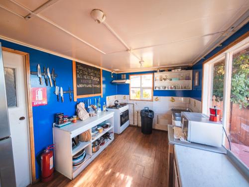 Eine Küche mit blauen Wänden und weißen Geräten in der Unterkunft Hostel Patagonia Backpackers in Puerto Natales