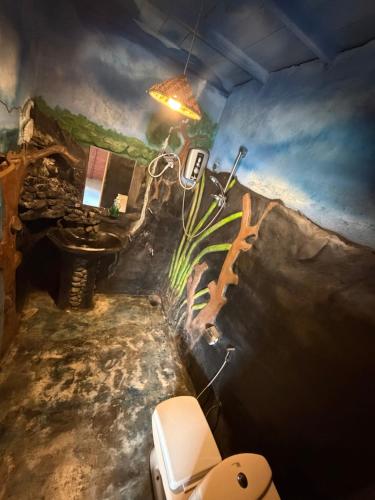 a bathroom with a painting on the wall and a toilet at Okan Rock Hostel Ella in Ella