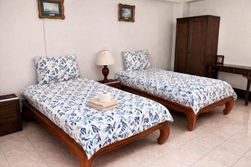 a bedroom with two beds with blue and white sheets at Chanathinat Place in Udon Thani