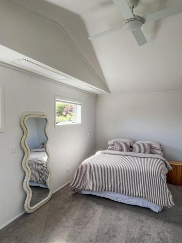 a bedroom with a large bed and a mirror at Mapua Village Modern Studio in Mapua