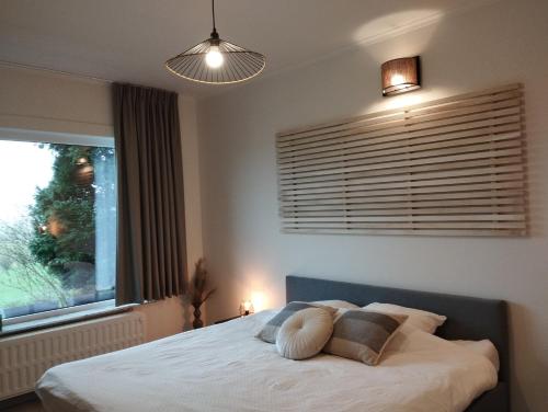 a bedroom with a bed with a window and a lamp at Vakantiehuis 't Leideveld in Maarkedal