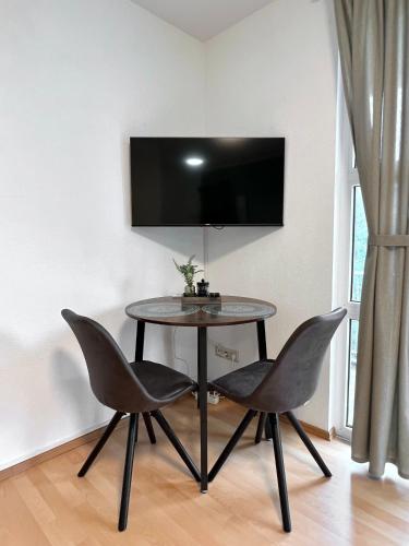 a table with two chairs and a tv on a wall at Modern, Gemütlich mit WLAN, TV in Essen