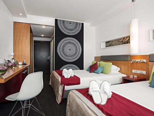 ein Hotelzimmer mit zwei Betten und einem Schreibtisch in der Unterkunft Novotel Roma Eur in Rom