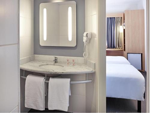 a bathroom with a sink and a bed in a room at ibis Londrina Shopping in Londrina