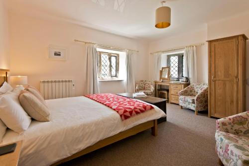 a bedroom with a large bed and a chair at Swarthmoor Hall in Ulverston