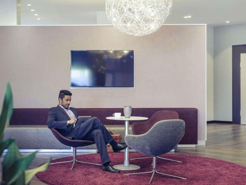 a man sitting in a chair in a room at Mercure Düsseldorf Kaarst in Kaarst
