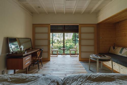 a bedroom with a bed and a desk and a table at 一棟貸し古民家宿「nagare」 in Iijima