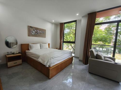 a bedroom with a bed and a couch and windows at Coast Pearl Hotel in Phú Quốc