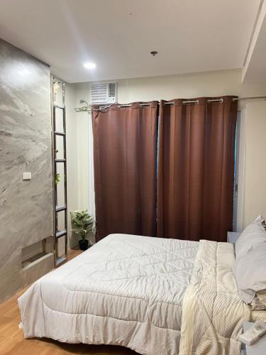 a bedroom with a large bed and brown curtains at Primavera Citta Verde in Balulang