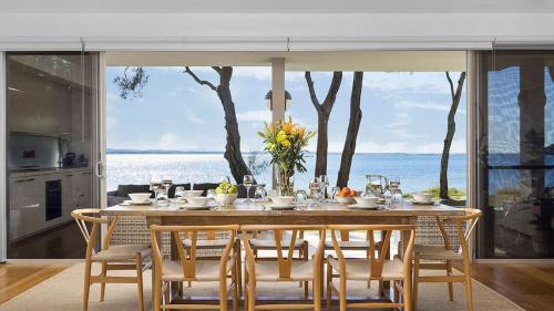 a dining room table with chairs and a view of the ocean at Paradiso Beach House in Salamander Bay