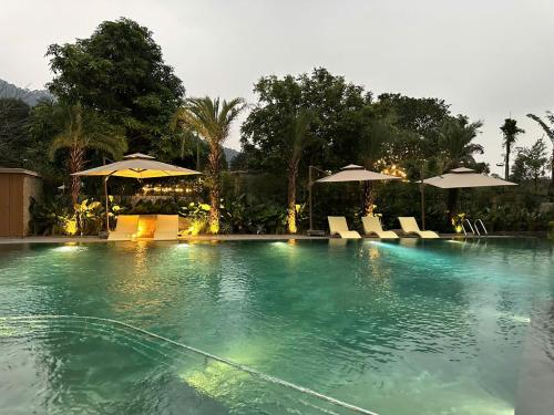 a large swimming pool with umbrellas and chairs in it at Rivana Retreat in Sóc Sơn