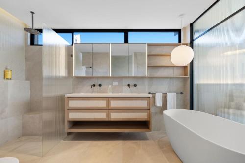a bathroom with a sink and a tub and a mirror at Solis Villa in Pottsville