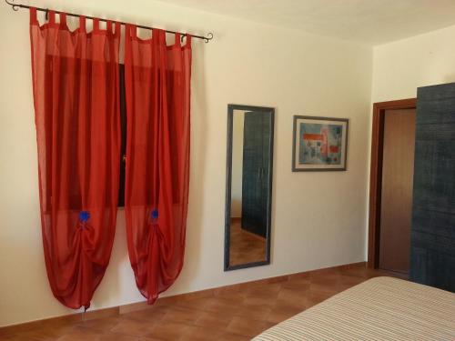 una camera da letto con tende rosse e specchio di La Casetta di Sara a Lampedusa