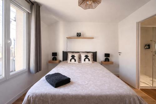 a white bedroom with a large bed with two pillows at Appartement Cosy Trelazé in Trélazé