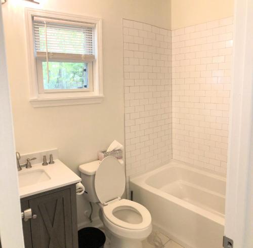 a bathroom with a toilet and a tub and a sink at LakewoodLyon Park Renovated Cottage Near Duke 23A in Durham