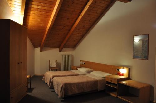 a bedroom with two beds and a wooden ceiling at Hotel Ideal in Sarche di Calavino