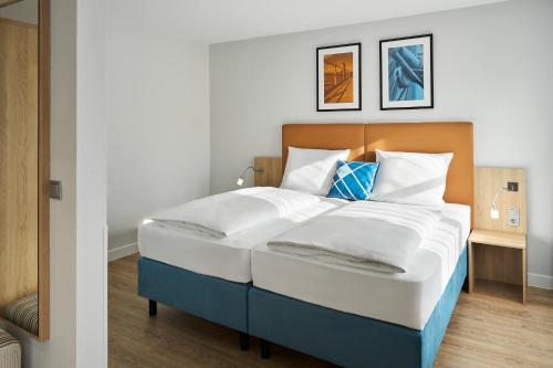 a bedroom with a large bed with white and blue at Four Points Flex by Sheraton Kiel in Kiel