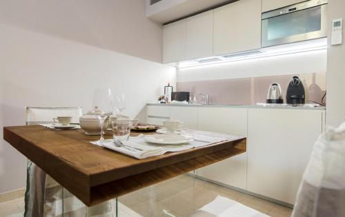uma cozinha com uma mesa de madeira com pratos e copos em Italianflat - Arena di Verona Rensi em Verona