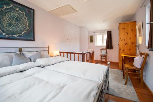 a bedroom with a large white bed and a desk at Schwarzwald Ferienhäuser in Haslach im Kinzigtal