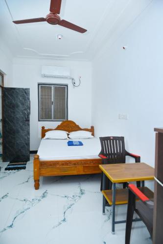a bedroom with a bed and a table and a ceiling fan at Le Lagrave Inn in Pondicherry