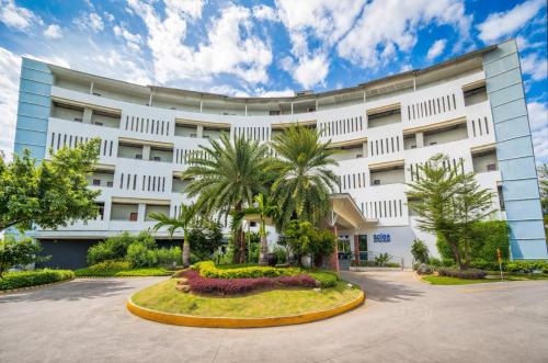 a large white building with palm trees in front of it at Solea Seaview Resort in Mactan
