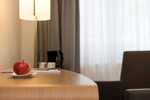 an apple on a plate on a table in a hotel room at Mercure Hotel Saarbrücken Süd in Saarbrücken