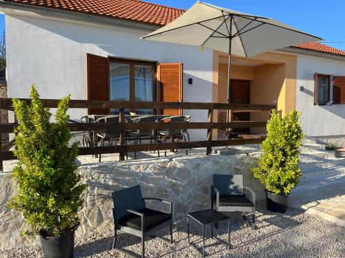 a house with a patio with chairs and an umbrella at Peaceful New Country House with Saltwater Pool in Brgud